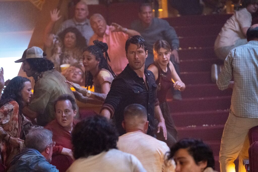 Glen Powell and Daisy Edgar Jones helping people inside a theater - Twisters