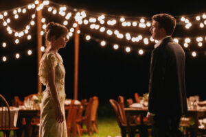 Chris Evans and Dakota Johnson standing across each other in Materialists