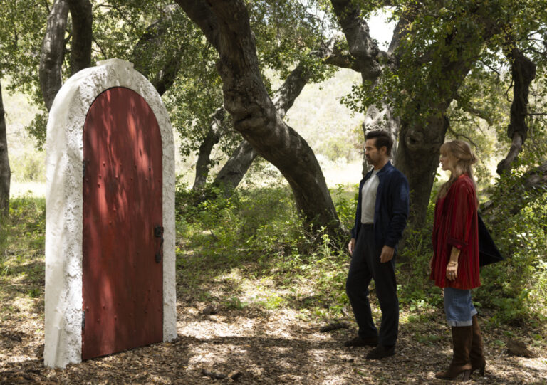Colin Farrel and Margot Robbie in front of a red door in A Big Bold Beautiful Journey
