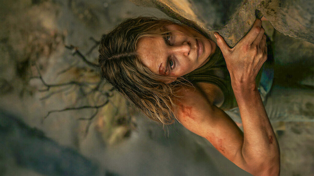Apex movie review. Charlize Theron hanging on a rock wall